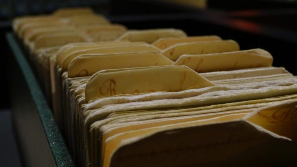 Vintage file folders organized in a row inside a dimly lit room.