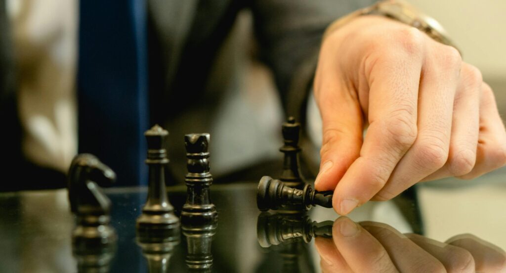 Capital Group Hand moves chess piece in strategic game setting, reflecting planning and decision-making.