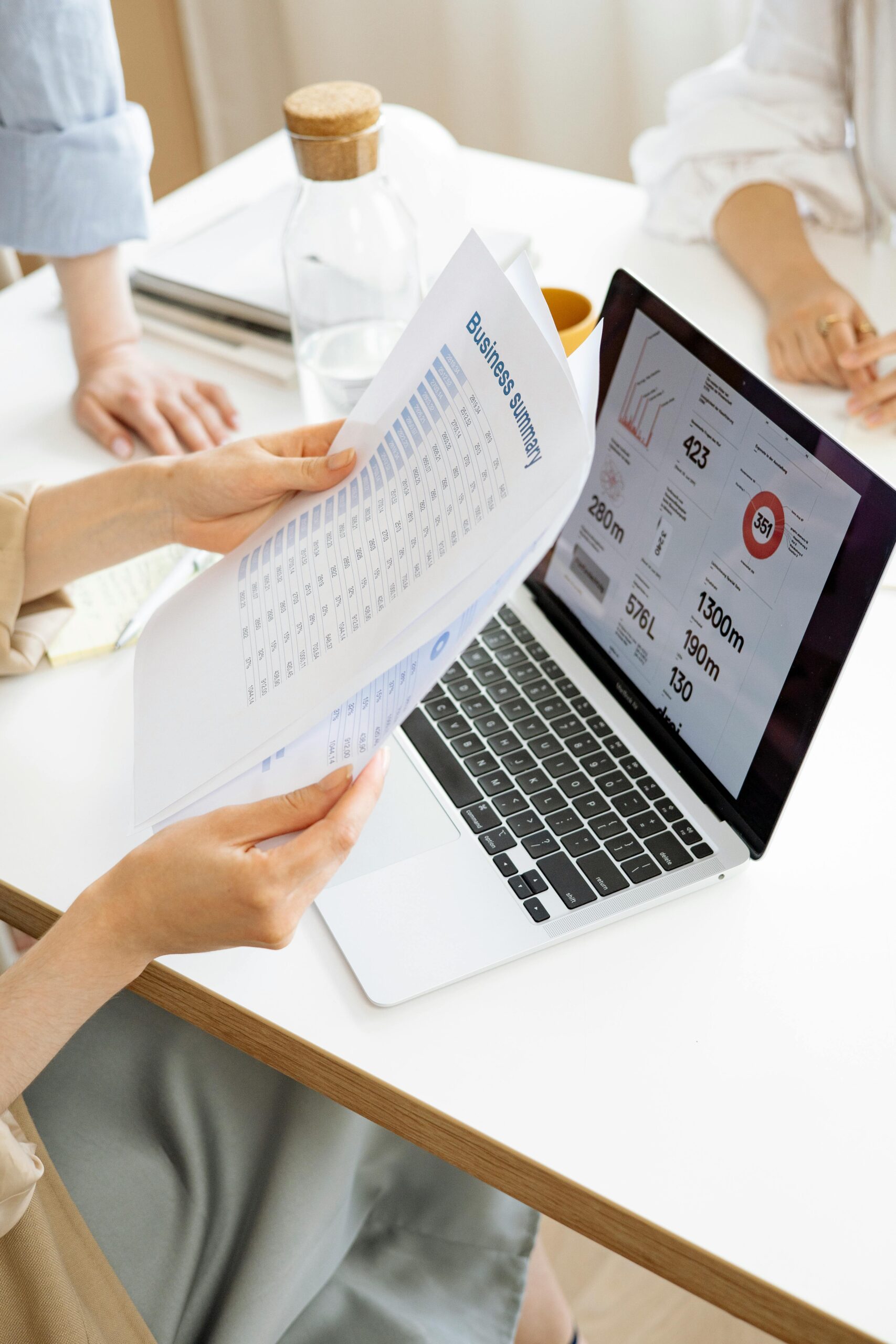 Modern office setting with a business report and laptop display on a white desk.